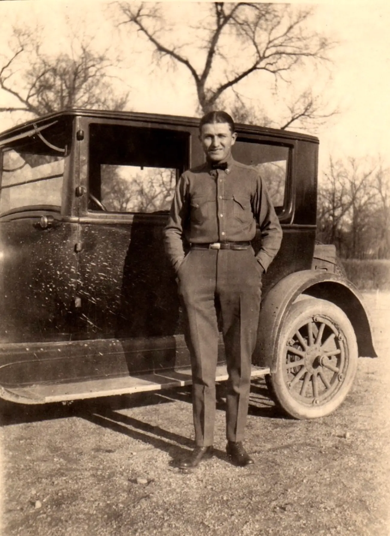 H.H. Fisher standing beside an early automobile
