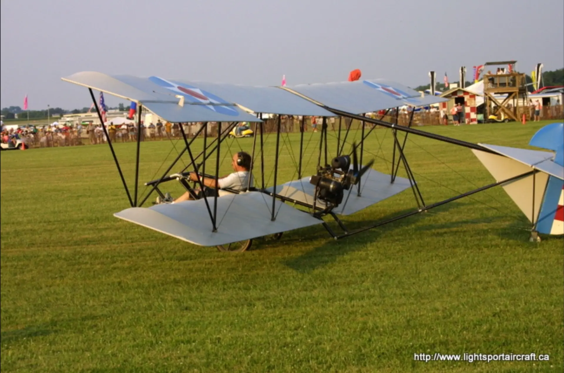 An ultralight airplane on the grass at an airshow