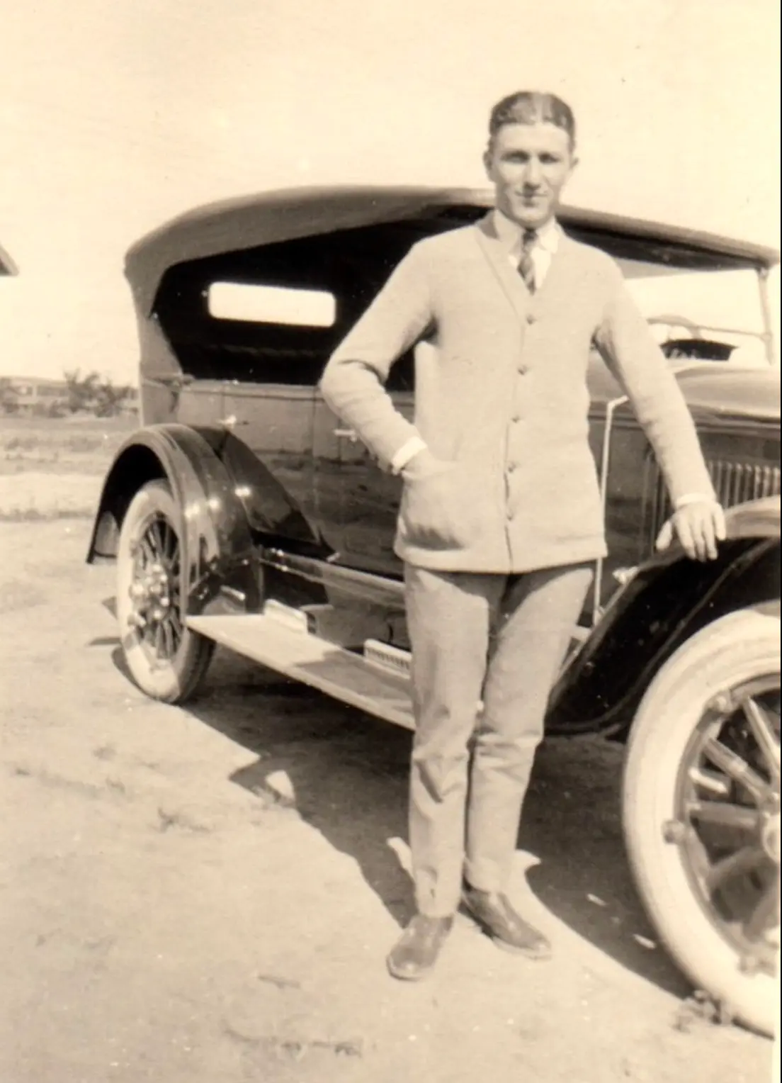 H.H. Fisher leaning on a touring car